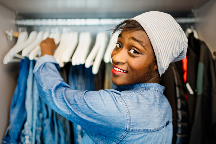 Portrait of young African woman, open wardrobe on background