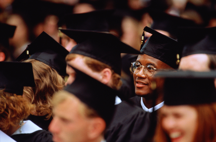 Graduates at graduation ceremony (focus on young man in glasses)